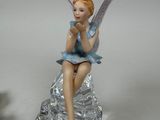a figurine of a fairy sitting on a glass plate