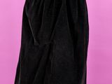 une jupe noire posée sur un mannequin, devant un fond rose