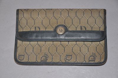 un sac à main beige et noir orné d'un monogramme, posé sur une surface blanche