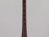 an old wooden flute on a clear stand on a white surface