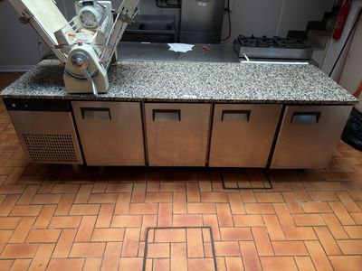 une photo d'une cuisine professionnelle équipée d'appareils en acier inoxydable et de plans de travail en granit