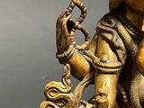 a gold statue of a man holding a snake