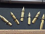 six fountain pens are lined up in a row on a table