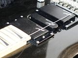 a close up of a black electric guitar on a black blanket