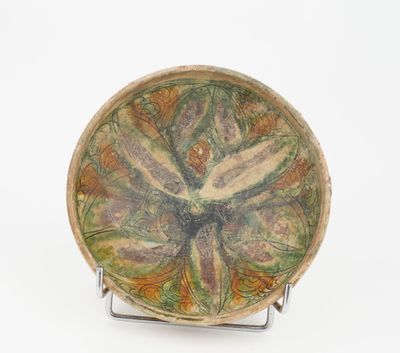 a plate with a flower design on it on a stand