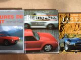 trois livres posés sur une table, à côté d'une voiture de sport rouge et d'une voiture de sport bleue