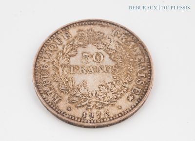 une vieille pièce de monnaie posée sur une surface blanche, sur laquelle figure un blason