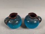 two blue vases sitting next to each other on a table
