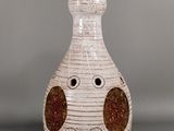 a white vase with a brown spot on it and a white cord plugged into it