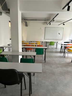 tables and chairs in a room with a white board and a whiteboard