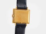 a close up of a gold plated watch on a black leather strap