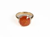 un gros plan d'une bague ornée d'une pierre orange entourée de diamants