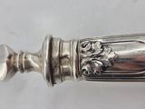 an antique silver spoon with a decorative handle on a white surface