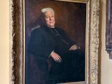 le portrait d'un homme assis sur une chaise à côté d'une horloge