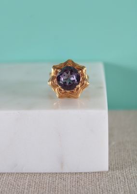 un gros plan d'une bague en or ornée d'une pierre violette au centre