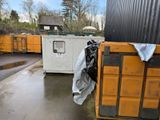 une benne à ordures située à côté d'un immeuble et recouverte d'une bâche