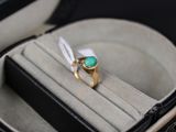 une bague dans un écrin, sertie d'une pierre verte