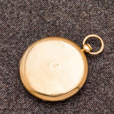 une vieille montre de poche en or, avec une chaîne suspendue sur le côté