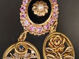 deux boucles d'oreilles dorées ornées de pierres noires et roses sur un fond noir