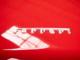 a picture of a red car with a chrome emblem on it