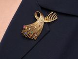 a close up of a woman wearing a gold brooch with multi colored stones