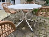 a white table with four chairs around it on a stone patio