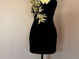 une robe noire posée sur un mannequin, devant un mur rose