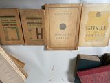 several old books are sitting on a table next to a stack of books
