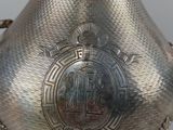 a silver vase with a metal handle on a table
