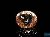 un diamant jaune sur une surface noire, avec un reflet
