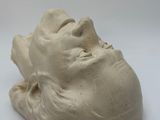 a clay sculpture of a man ' s face on a white surface