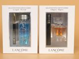 two bottles of perfume in a white box on a brown surface