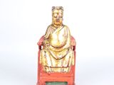 une petite statue représentant un homme assis sur une chaise rouge