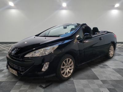 La voiture noire est garée sur un sol en carrelage à damier.