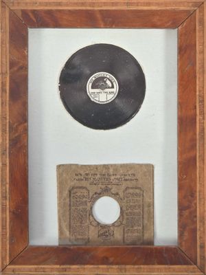 un vieux disque dans un cadre en bois, avec un bout de papier en dessous