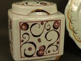 a white container with a design on it next to a plate with a lid