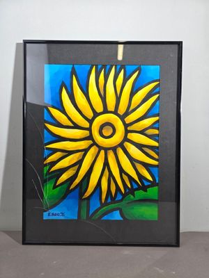 tableau représentant un tournesol jaune dans un cadre noir, posé sur une table