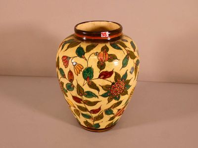 a yellow vase with red and green flowers on it