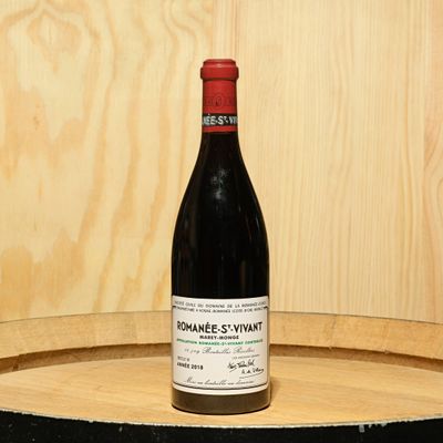 a bottle of wine sitting on top of a barrel