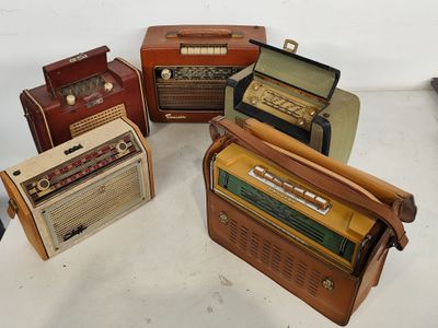 Plusieurs radios à l'ancienne sont alignées sur une table
