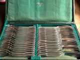 a green case filled with silverware on a wooden floor