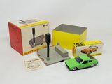 une petite voiture verte posée à côté d'une boîte contenant d'autres petites voitures
