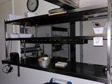 une cuisine avec une horloge accrochée au mur et une poubelle posée par terre