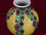 un vase jaune orné de fleurs rouges sur fond rouge