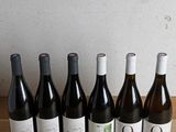 several bottles of wine are lined up on a wooden table