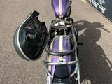 a purple motorcycle parked in a parking lot with a helmet on the back