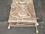 a silver plate with a candle on it on a black cloth