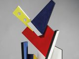 un gros plan d'une sculpture posée sur une surface blanche, avec un fond gris