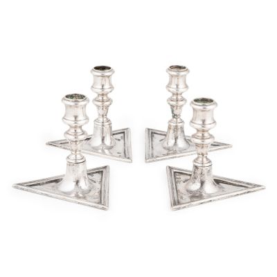 une paire de bougeoirs en argent posés sur un socle, sur fond blanc