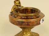 a small bronze statue of a boy sitting on a bowl